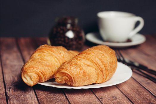 croissants in a plate on the table meal dessert for breakfast a cup of coffee. High quality photo
