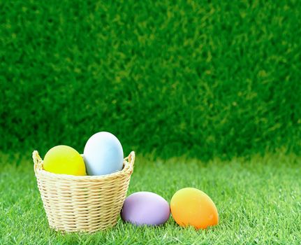 Colorful easter eggs in the basket on green grass background with copy space