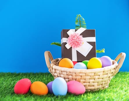 Colorful easter eggs in the basket on green grass background with copy space