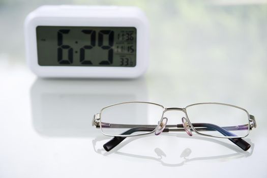 Close up Eye glasses and Digital clock on table at home