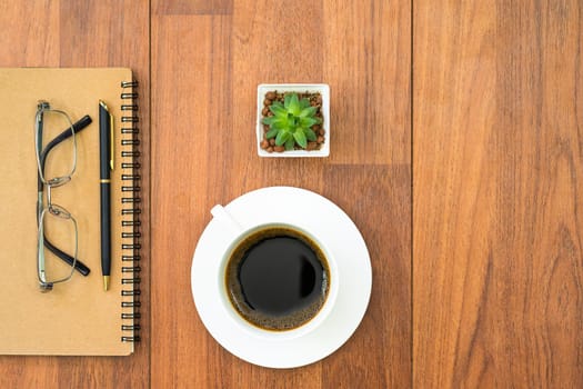 Top view eyeglasse and pen on notepad and coffee cup on wood deck