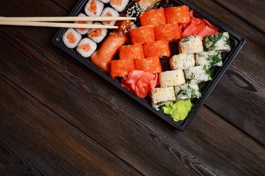 sushi rolls with seafood on a wooden table and chopsticks. High quality photo