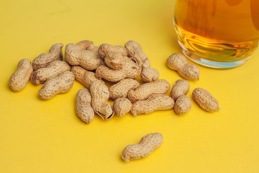 peanuts in shells beer mug snack alcohol yellow background. High quality photo