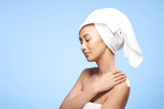 woman of asian appearance bare shoulders towel on head shower rest. High quality photo