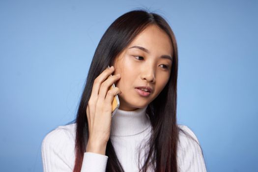 woman korean appearance talking on mobile phone on blue background. High quality photo