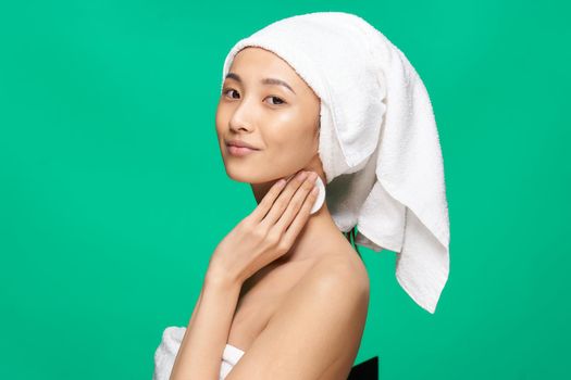 woman of asian appearance naked shoulders towel on head green background studio. High quality photo