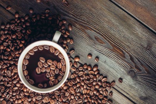 cup with aromatic drink and coffee beans on wooden background top view. High quality photo