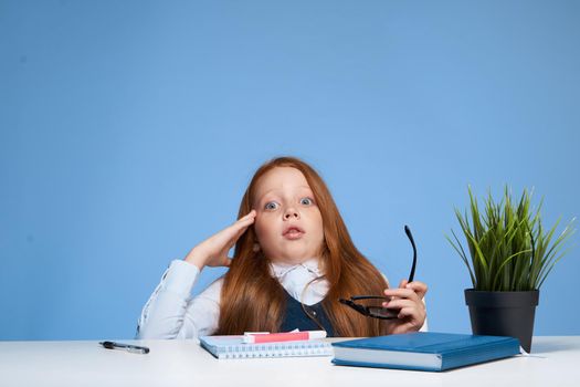 cute red-haired girl student sitting at the table school education. High quality photo