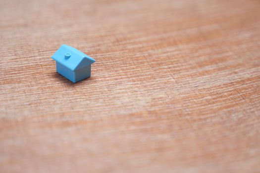 Symbol of house on wood background. Real estate buy sell home icon property house model. Blue toy home property market housing mortgage loan. Minimal design one single miniature house with copy space