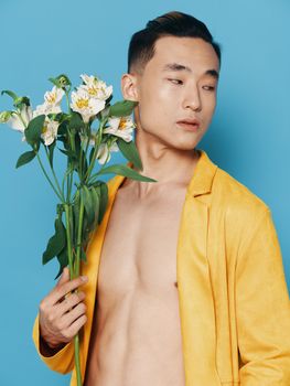 Romantic Asian guy with a bouquet of white flowers and in a yellow coat. High quality photo