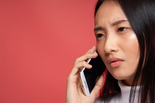 pretty woman with phone in hand communication close-up studio red background. High quality photo
