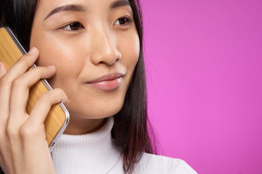 woman asian appearance talking on the phone cropped view studio pink background. High quality photo