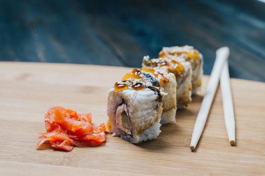 sushi rolls chopsticks ginger red on wooden board. High quality photo