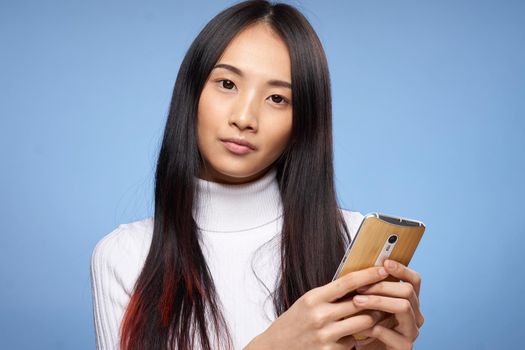 woman of asian appearance with a phone in hands internet technology communication close-up. High quality photo