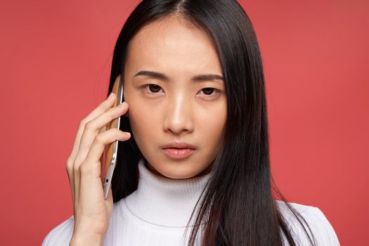 woman of asian appearance talking on the phone technology emotions red background. High quality photo