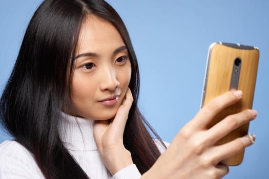 attractive woman asian appearance phone in hands technology lifestyle blue background. High quality photo