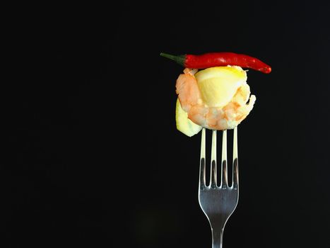 The king's prawn is peeled with a slice of lemon and chilli, isolated on a black background. High quality photo