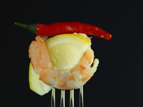 The king's prawn is peeled with a slice of lemon and chilli, isolated on a black background. High quality photo