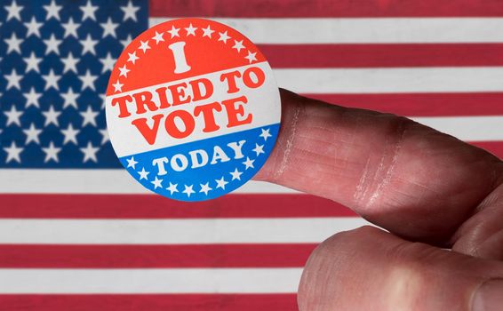 Finger with I Voted button in front of voting stickers given to US voters. This illustrates state laws to suppress votes and make it difficult to vote