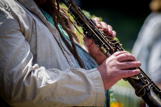 Close-up of the hands of a man playing the clarinet in the street