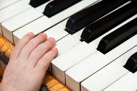 Detail of the hand of a baby playing the keys of a piano