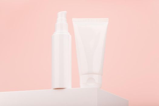 Two white cosmetic tubes on podium shot from epic angle against light pink background with copy space. Concept of skin care and beauty