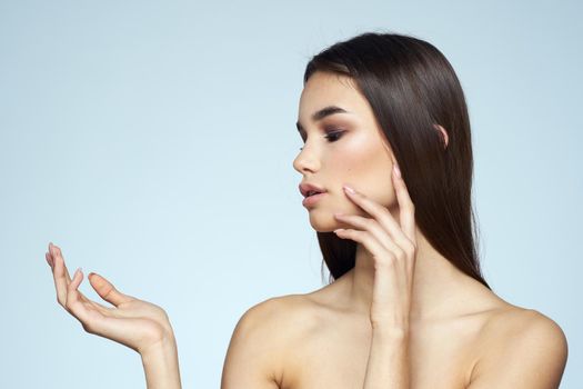 Woman with naked shoulders long hair clean skin cropped view blue background. High quality photo