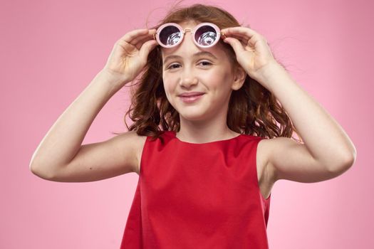girl with curly hair sunglasses childhood joy pink background. High quality photo
