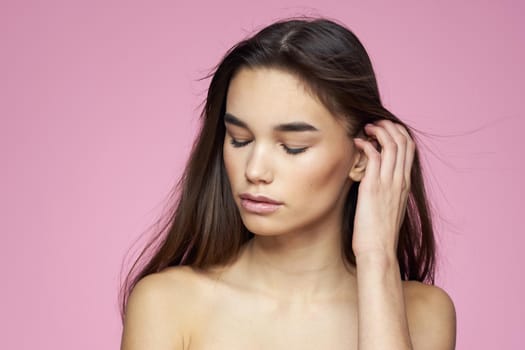brunette bare shoulders clear skin body care pink background. High quality photo