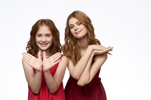 Mom and little daughter wearing red dresses joy friendship lifestyle light background. High quality photo