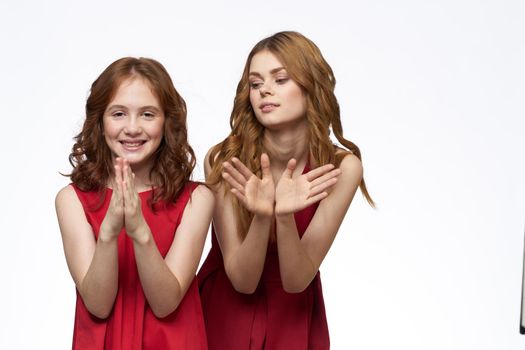 Mom and little daughter wearing red dresses joy friendship lifestyle light background. High quality photo