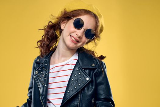 Girl in a yellow hat dark glasses fashionable clothes studio lifestyle childhood. High quality photo