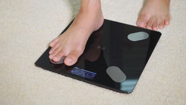 Asian young woman leg stepping standing on floor electric scales, female working out at home in living room, female stand on digital weighing machine. Healthy weight loss control concept, slow motion