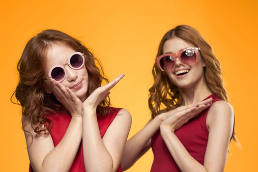 Two sisters and fun sunglasses fashion Friendship yellow background family. High quality photo