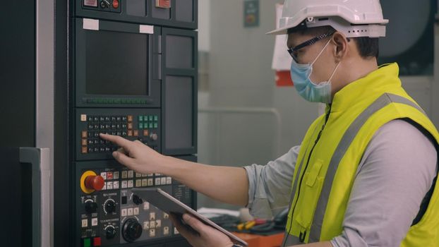 Asian factory worker man operating automated programming CNC milling control machine industry center at tool workshop manufacturing