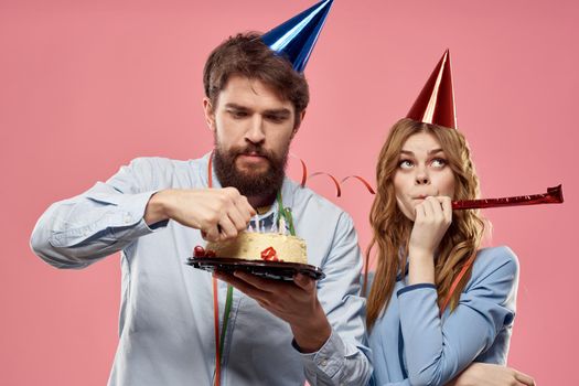 Party man and woman with cake on pink background corporate birthday. High quality photo