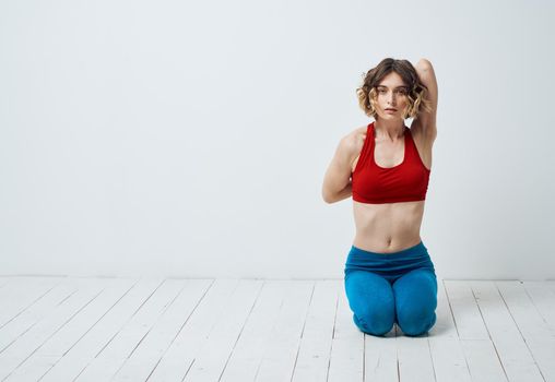 A woman in sportswear is doing yoga in a bright room and gesticulating with her hands. High quality photo