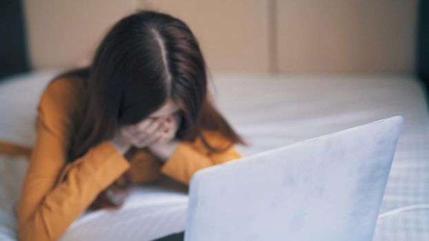 emotional woman lies in bed in front of laptop freelance discontent. High quality photo