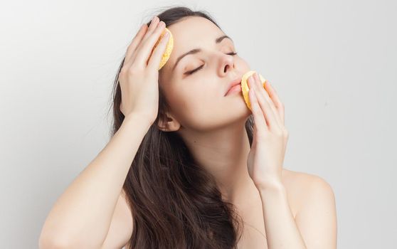 pretty brunette with bare shoulders sponge in hand grooming cropped view. High quality photo