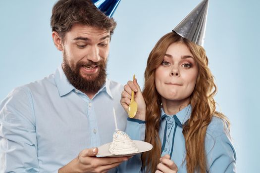 Cheerful man and woman with cake in a plate corporate party blue background. High quality photo