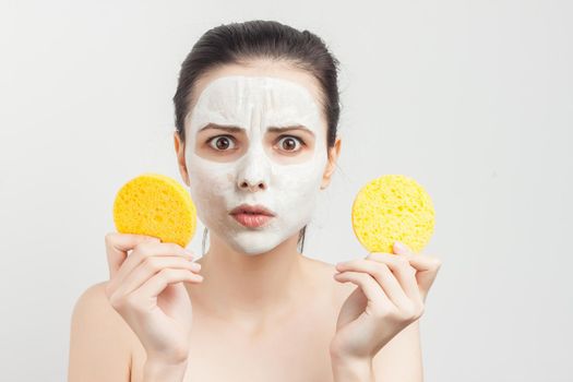 woman with bare shoulders wipes a mask on her face with sponges. High quality photo