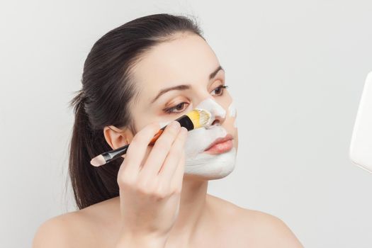 brunette brushing cream on face skin care cropped view. High quality photo
