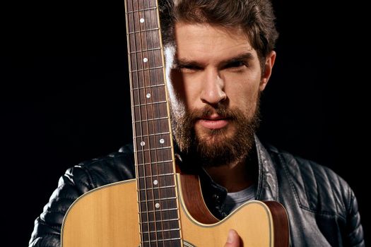 A man with a guitar in his hands leather jacket music performance rock star modern style dark background. High quality photo