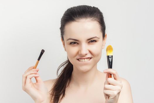 brunette with cream on her face brush in hands applying cream. High quality photo