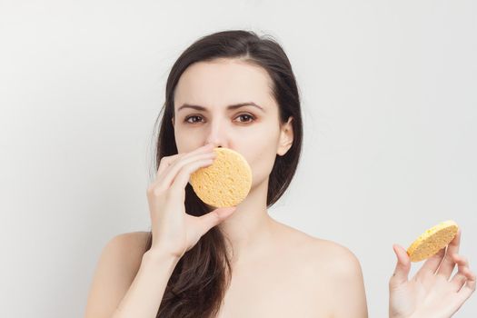 brunette with flowing hair naked shoulders sponge near face. High quality photo