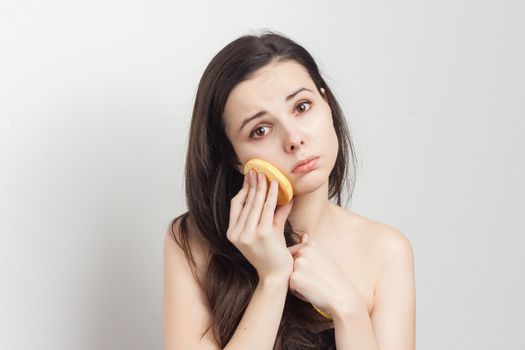 brunette with flowing hair naked shoulders sponge near face. High quality photo