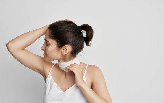 brunette with a bandaged neck holding her head health problems. High quality photo