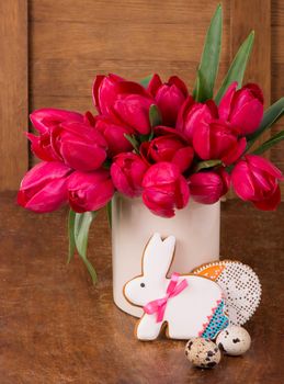 Pink tulips and easter bunny cookie on wooden background. Spring or easter concept