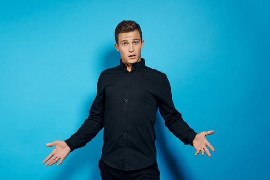 Cute man in black shirt emotions studio blue background. High quality photo