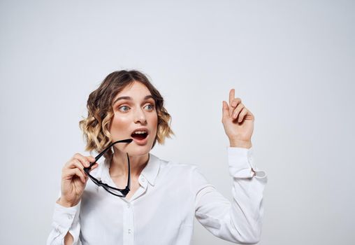 Emotional woman in a white shirt with glasses in her hands on a light background Copy Space. High quality photo